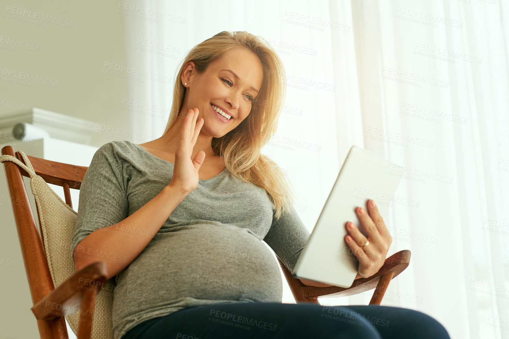 Buy stock photo Shot of a pregnant woman using her digital tablet while sitting on a rocking chair