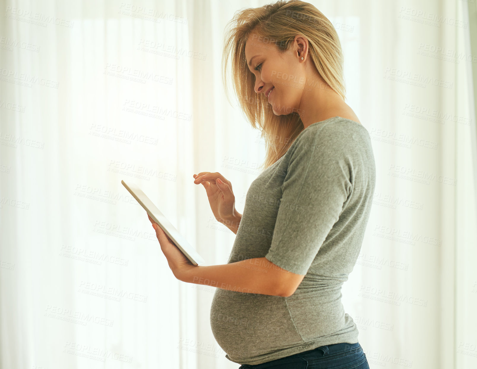 Buy stock photo Cropped shot of a pregnant woman using her digital tablet at home