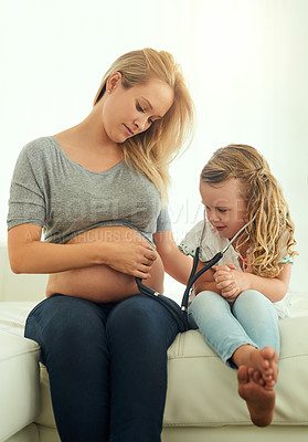 Buy stock photo Shot of a little girl using a stethoscope to listen to her mother's pregnant belly