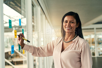 Buy stock photo Portrait of a confident businesswoman making notes on a glass wall in the office