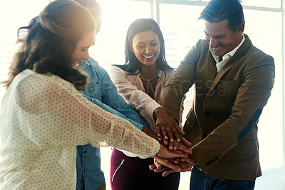 Buy stock photo Shot of a group of happy coworkers putting their hands on top of each other in the office