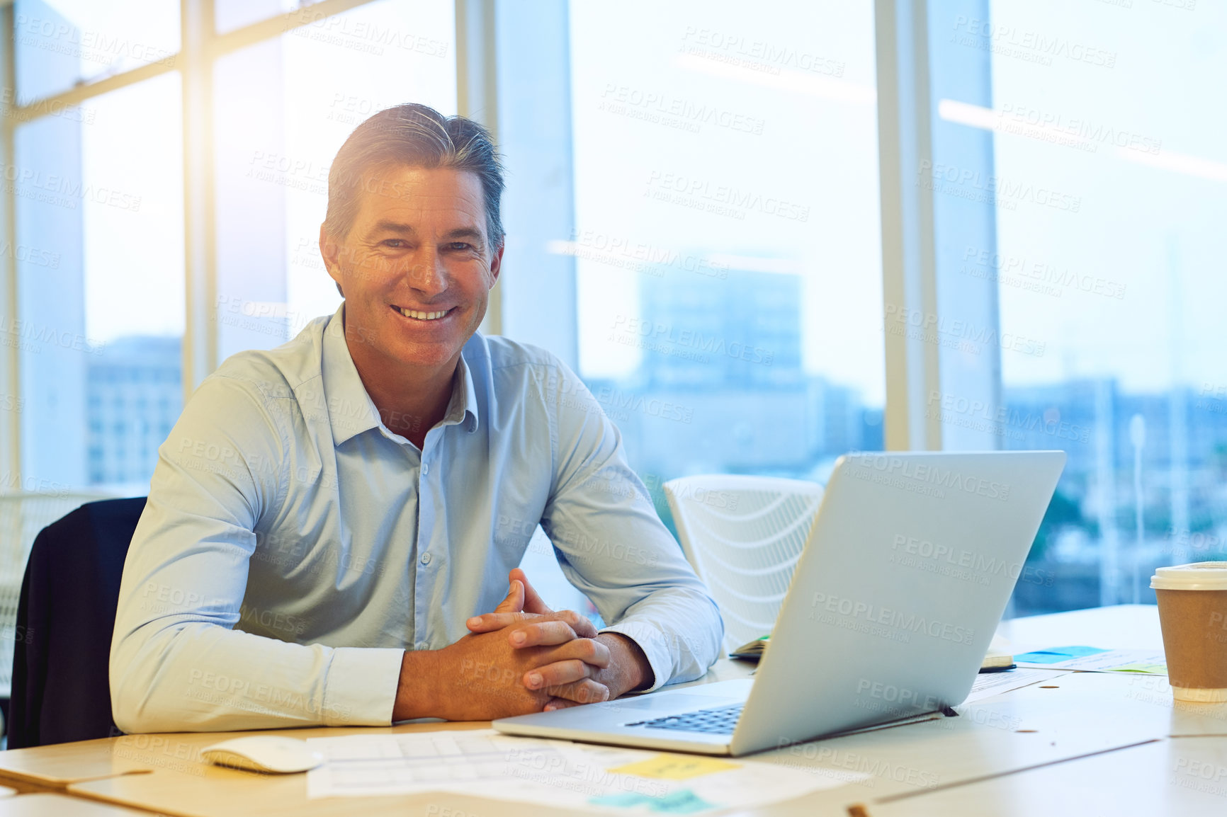 Buy stock photo Portrait of a happy hardworking businessman working on his laptop in the office