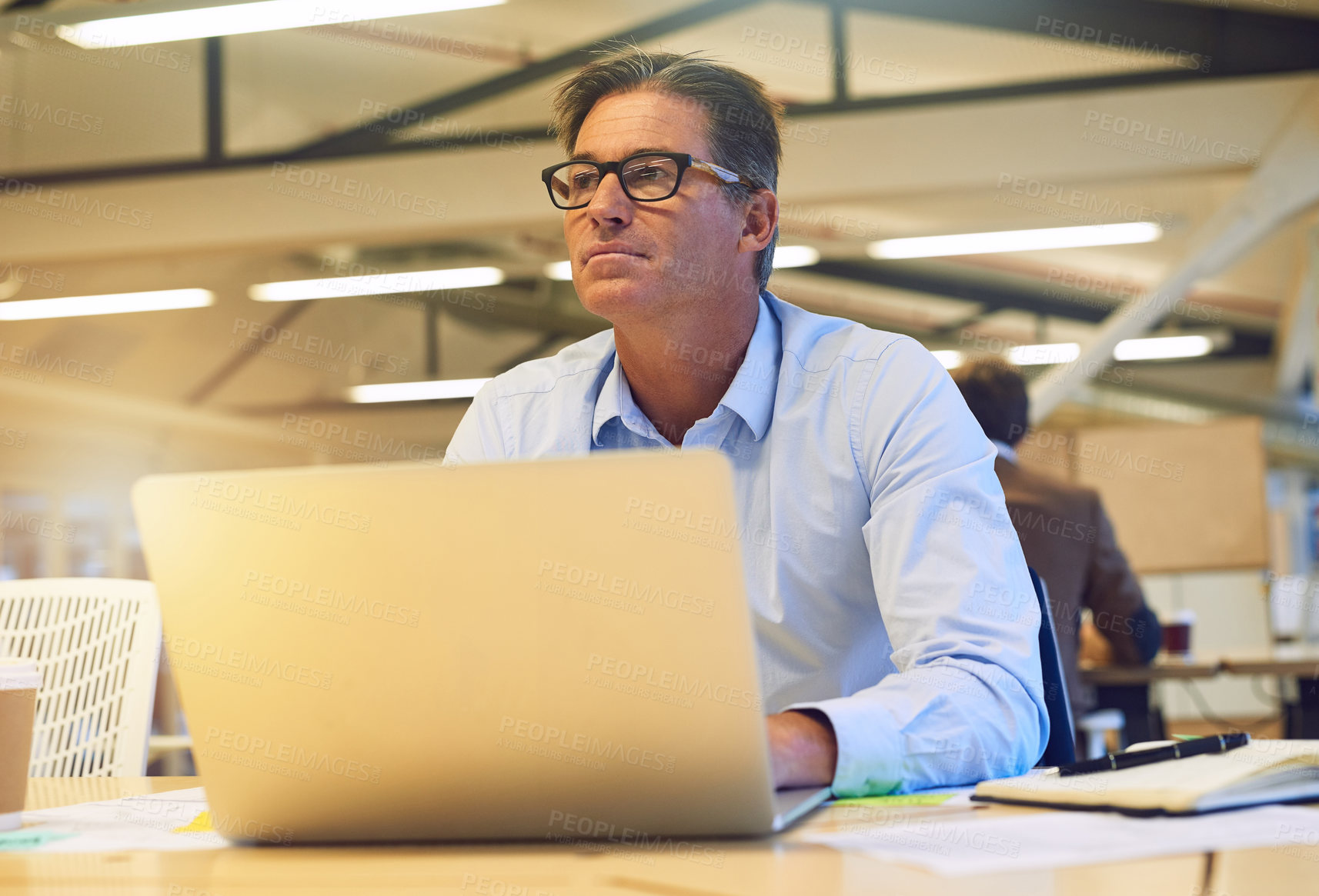 Buy stock photo Shot of a hardworking businessman using his laptop at his desk in the office