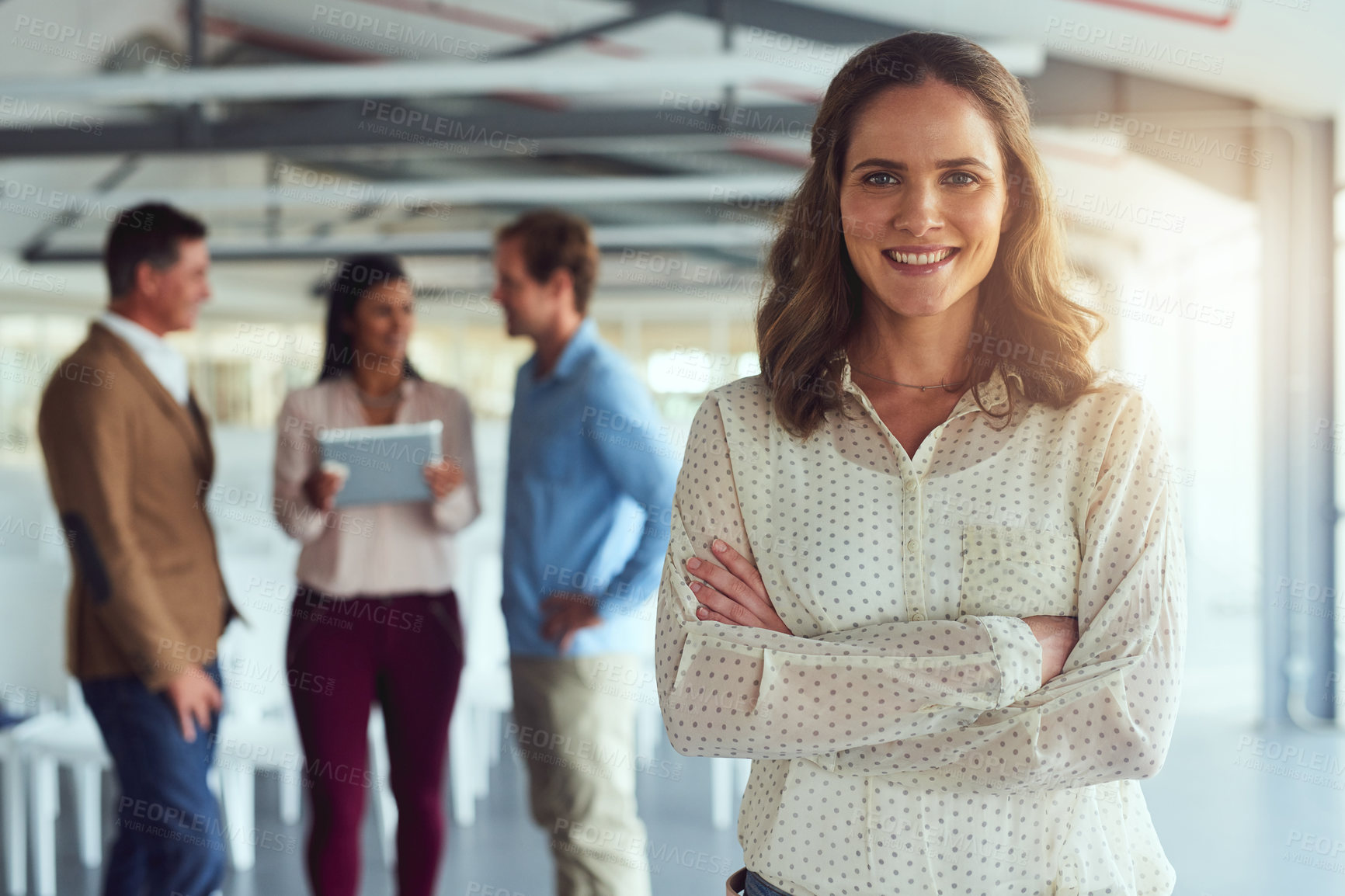 Buy stock photo Portrait of a confident businesswoman posing in the office while her colleagues brainstorm in the background