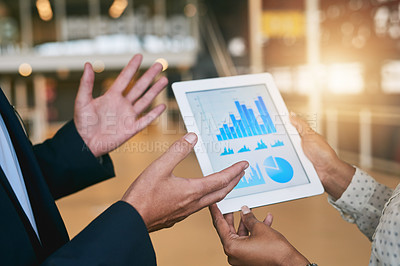 Buy stock photo Closeup shot of two unrecognisable businesspeople analysing graphs on a digital tablet in an office