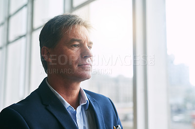 Buy stock photo Shot of a mature businessman looking out the window in an office