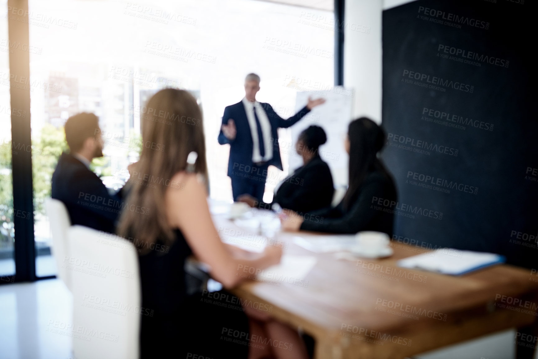 Buy stock photo Defocused shot of a team of businesspeople attending a presentation in the boardroom