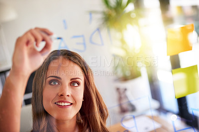 Buy stock photo Shot of an inspired young businesswoman laying out a business plan with adhesive notes against a glass wall