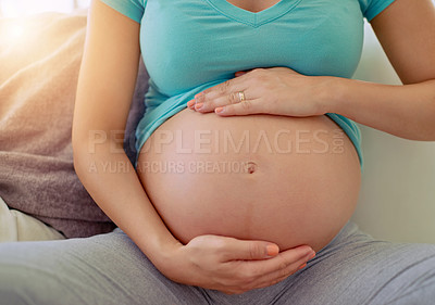 Buy stock photo Closeup shot of a pregnant woman holding her belly at home