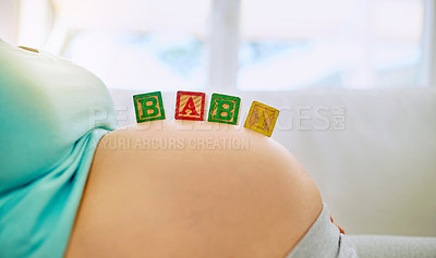Buy stock photo Closeup shot of a pregnant woman lying down with wooden baby blocks on her belly at home