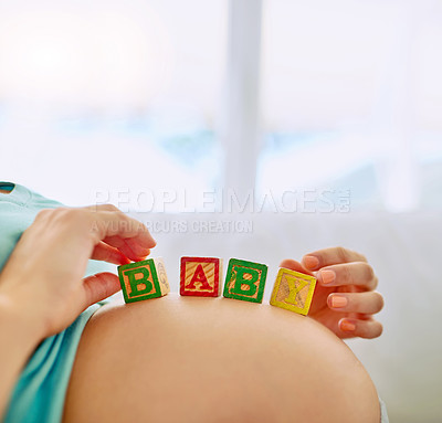 Buy stock photo Closeup shot of a pregnant woman lying down with wooden baby blocks on her belly at home