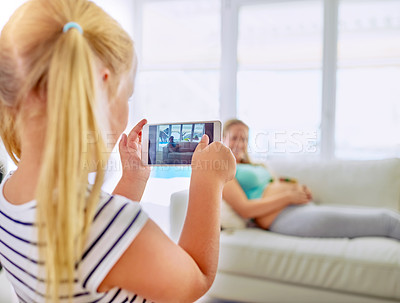 Buy stock photo Shot of a little girl taking a photo of her pregnant mother at home