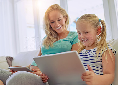 Buy stock photo Shot of a pregnant woman and her little daughter using digital tablets at home