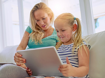Buy stock photo Shot of a pregnant woman and her little daughter using a digital tablet at home