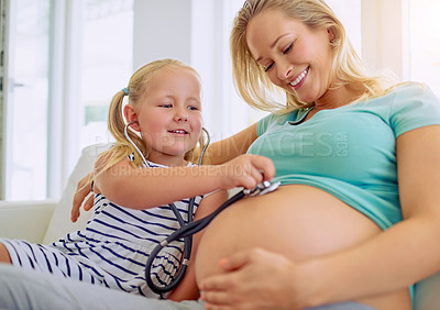 Buy stock photo Shot of a little girl using a stethoscope to listen to her mother's pregnant belly at home