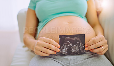 Buy stock photo Closeup shot of a pregnant woman holding a sonogram picture against her belly at home