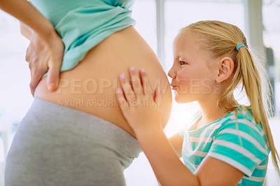 Buy stock photo Shot of a little girl kissing her mother's pregnant belly at home