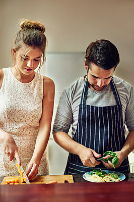 Buy stock photo Shot of a young couple preparing food together at home