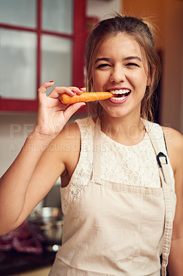 Buy stock photo Food, portrait or girl eating carrot in kitchen for wellness, health or vegan snack while cooking at home. Vegetable, face or teenage person in house for superfoods diet, nutrition or vitamin C snack