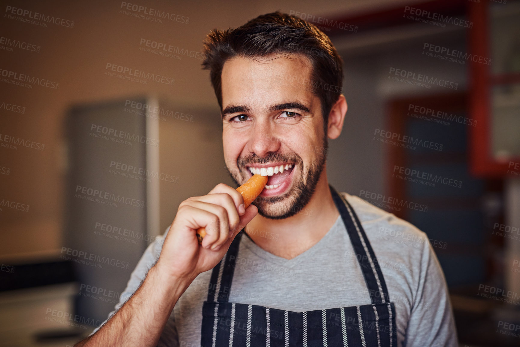 Buy stock photo Man, portrait and eating carrot with bite for health, nutrition or vegan diet for wellness. Male chef, vegetables and smile in kitchen for cooking with food and culinary hobby to prepare home dinner