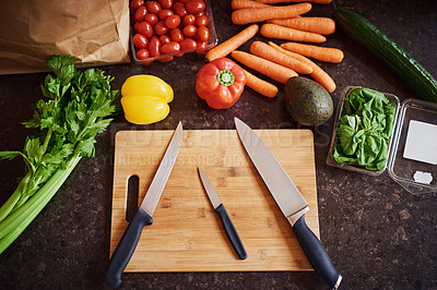 Buy stock photo High angle shot of a selection of fresh ingredients arranged around a chopping board on a kitchen counter