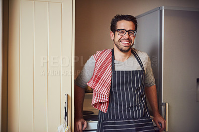Buy stock photo Portrait of a happy young man wearing an apron while posing in his kitchen at home