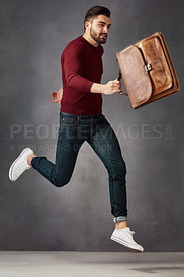 Buy stock photo Studio shot of a handsome young man posing with a bag against a dark background