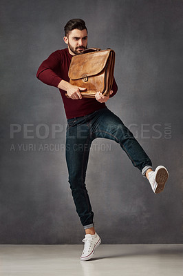Buy stock photo Studio shot of a handsome young man posing with a bag against a dark background