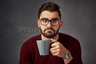 Buy stock photo Studio portrait of a handsome young man frowning while drinking coffee against a dark background