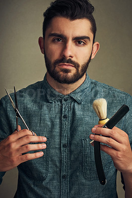 Buy stock photo Studio shot of a handsome young man holding a straight razor, scissor and a shaving brush in his hands