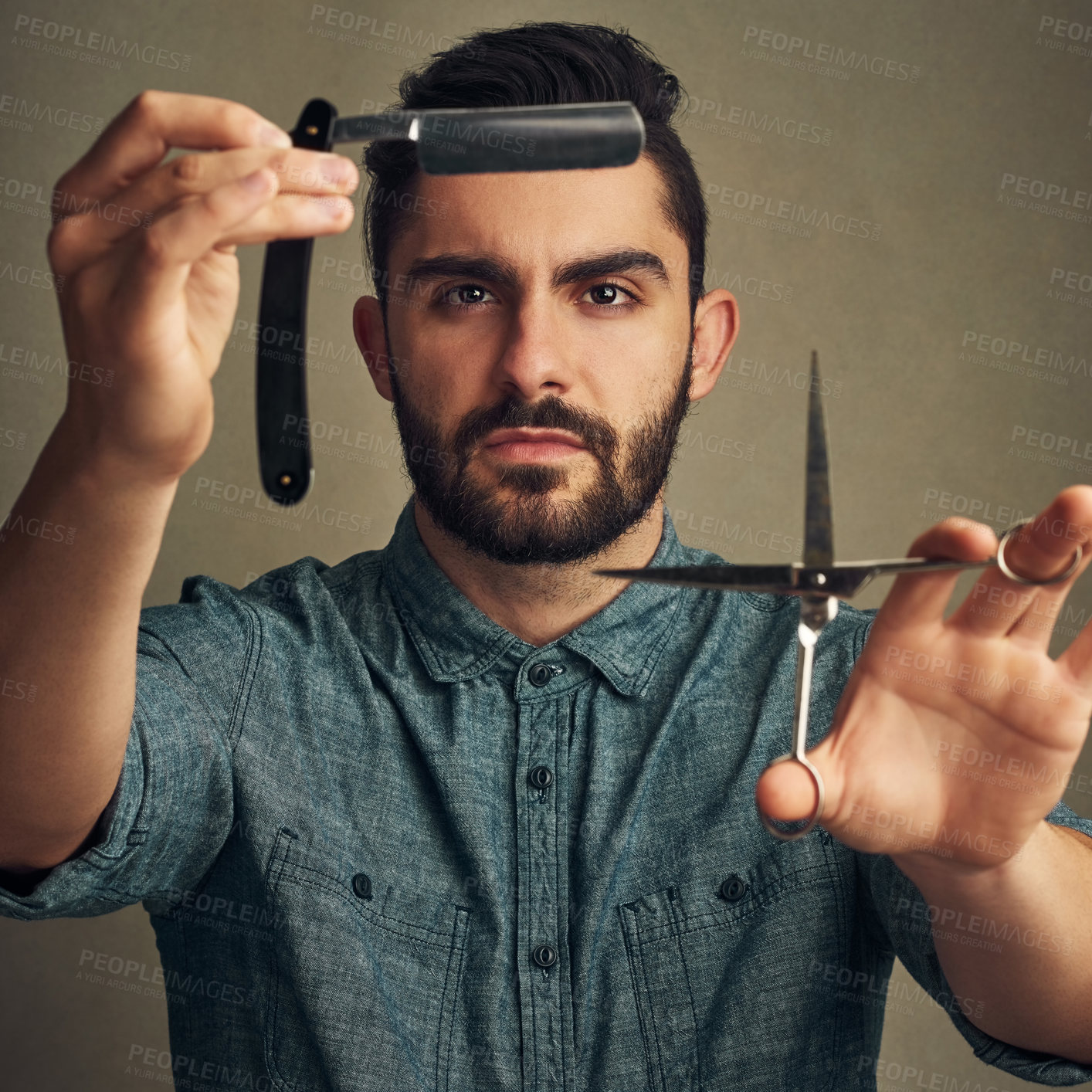 Buy stock photo Studio shot of a handsome young man holding a straight razor and a scissor in his hands