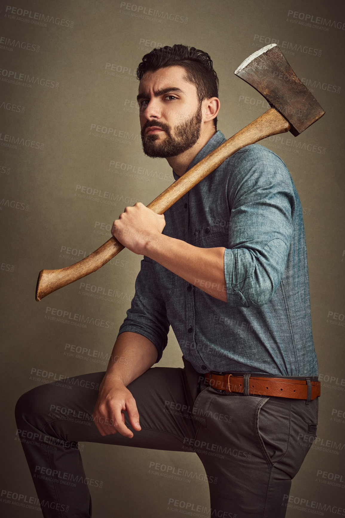 Buy stock photo Studio shot of a young man posing with an axe against a green background