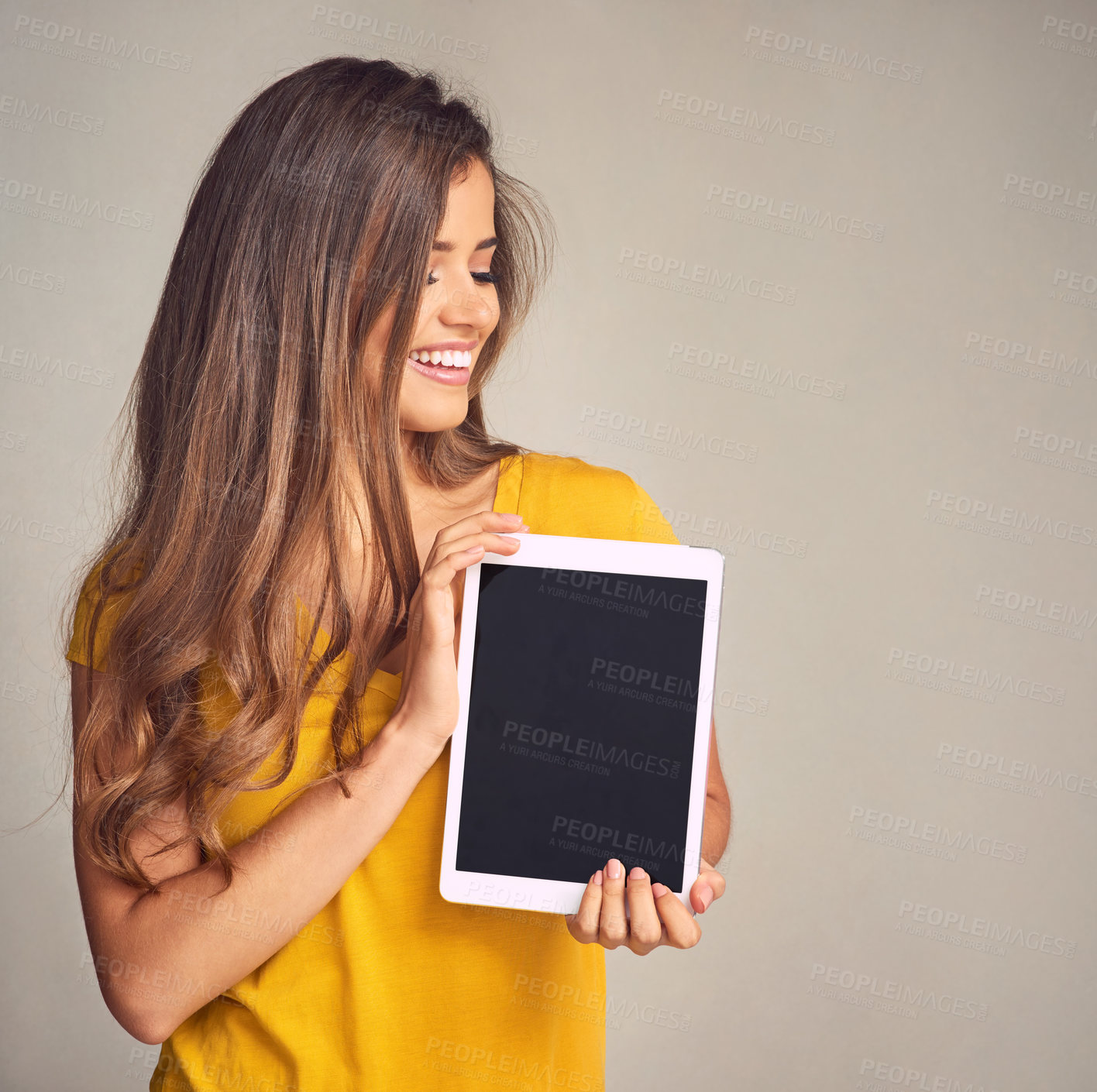 Buy stock photo Shot of an attractive young woman holding a digital tablet with a blank screen against a grey background