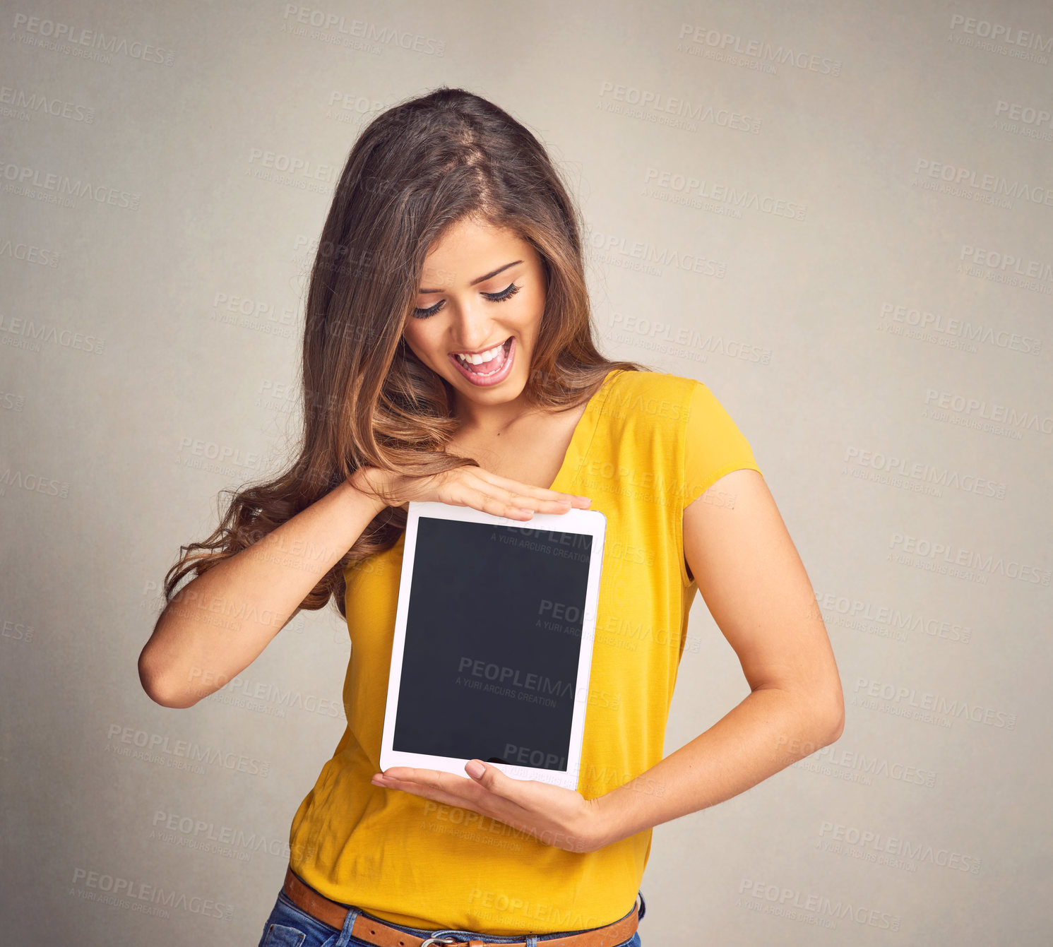 Buy stock photo Shot of an attractive young woman holding a digital tablet with a blank screen against a grey background