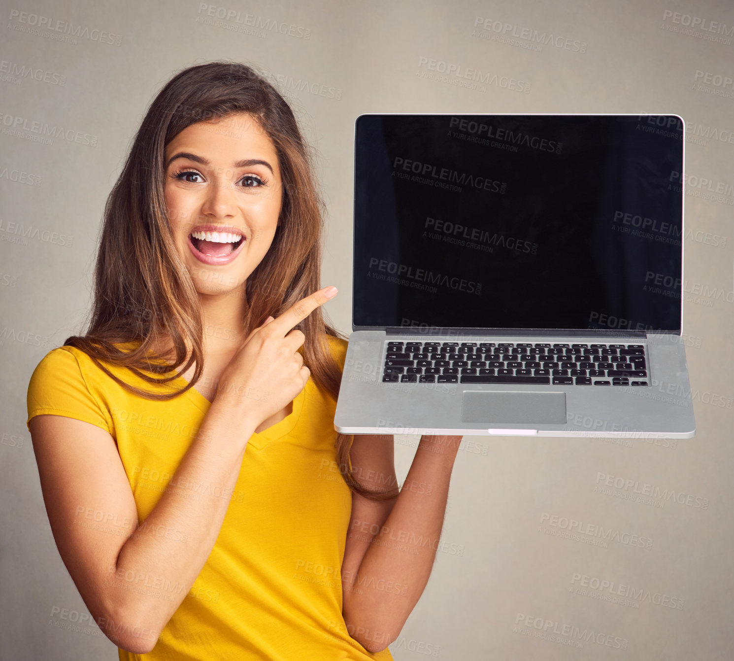 Buy stock photo Shot of an attractive young woman holding a laptop with a blank screen against a grey background
