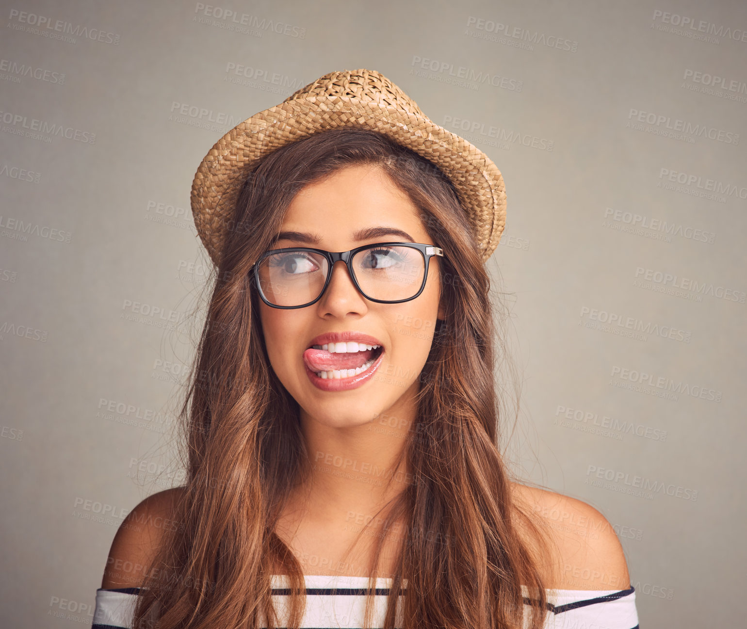 Buy stock photo Studio shot of an attractive young woman playfully sticking out her tongue against a gray background