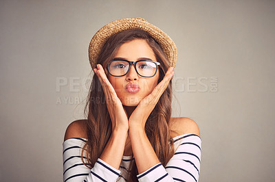 Buy stock photo Studio portrait of an attractive young woman making a playful facial expression against a gray background