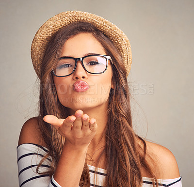 Buy stock photo Studio portrait of an attractive young woman blowing kisses against a gray background