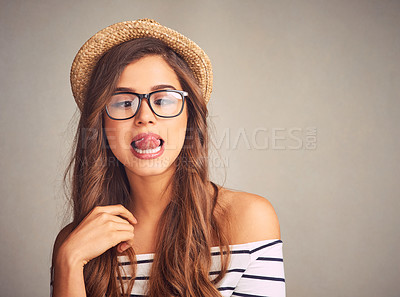 Buy stock photo Studio shot of an attractive young woman playfully touching her nose with her tongue against a gray background