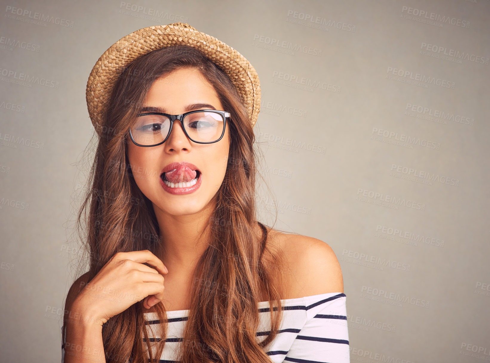 Buy stock photo Studio shot of an attractive young woman playfully touching her nose with her tongue against a gray background