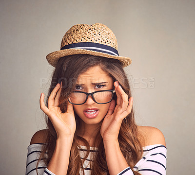 Buy stock photo Studio portrait of an attractive young woman peeking over her glasses with attitude against a gray background