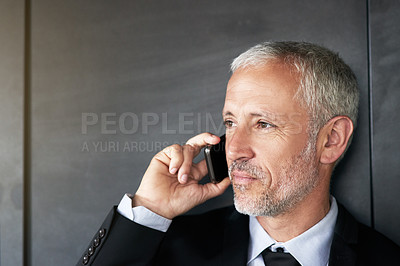 Buy stock photo Cropped shot of a handsome mature businessman standing and making a call in the office