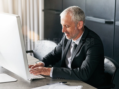 Buy stock photo Cropped shot of a handsome mature businessman sitting down and working on his computer in the office