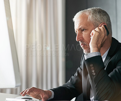 Buy stock photo Cropped shot of a handsome mature businessman sitting in the office in front of the computer while on his phone