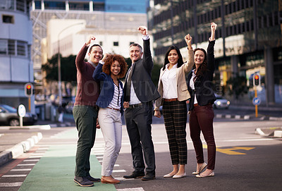 Buy stock photo Shot of a motivated business team putting their hands up for success while standing in the middle of a street
