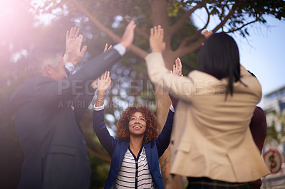Buy stock photo Low angle shot of a business team huddling together for high fives while standing outside