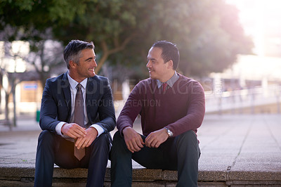 Buy stock photo Shot of two businessmen having a discussion while seated outside on steps