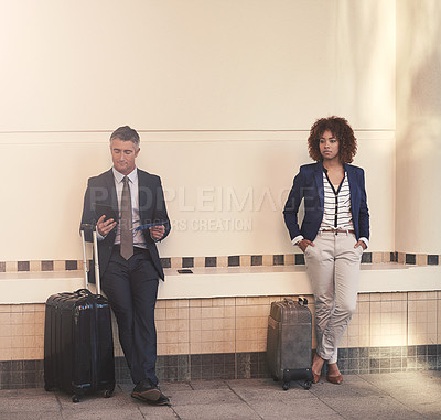 Buy stock photo Shot of two businesspeople standing with their luggage and waiting for the train in the subway