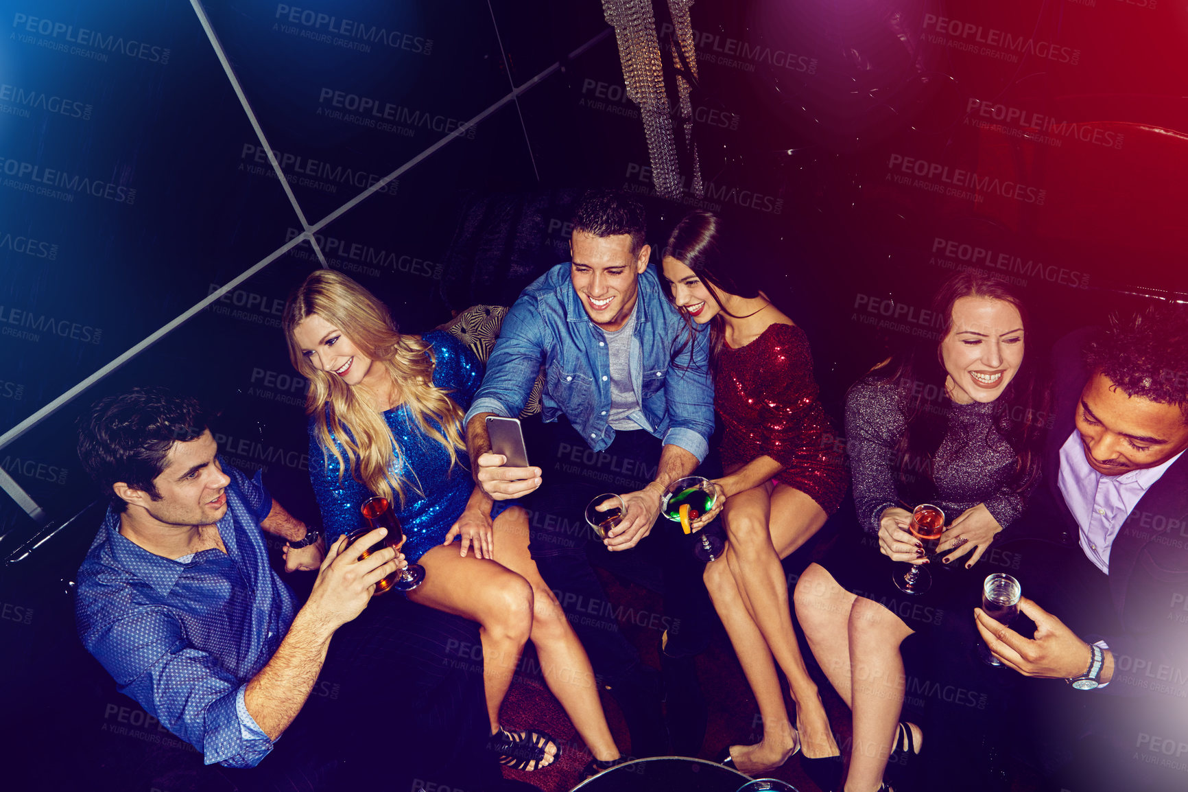 Buy stock photo Shot of a group of friends taking selfies on a mobile phone at a party