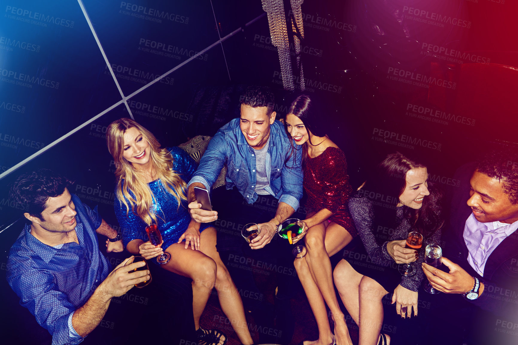 Buy stock photo Shot of a group of friends taking selfies on a mobile phone at a party